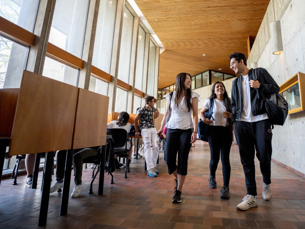 Three students smiling walking down a hall