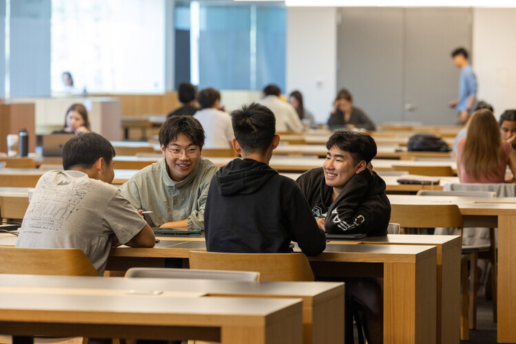 Four students sitting together at a desk smiling